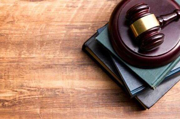 Legal Law concept - Open law book with a wooden judges gavel on table in a courtroom or law enforcement office. Copy space for text.